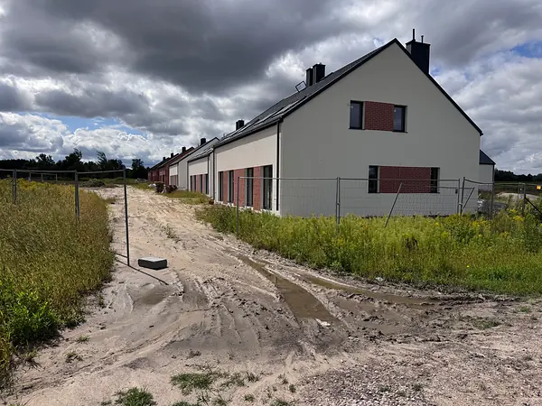 Domy osiedla widziane od strony drogi dojazdowej, sierpień 2026